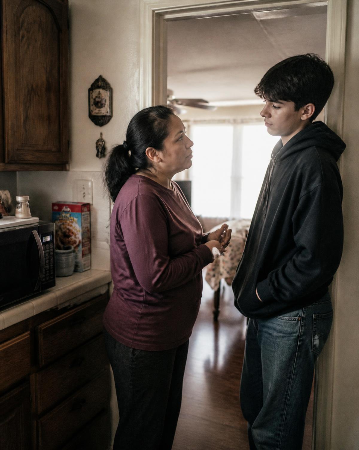 A mother and her teenage son talking in a kitchen doorway